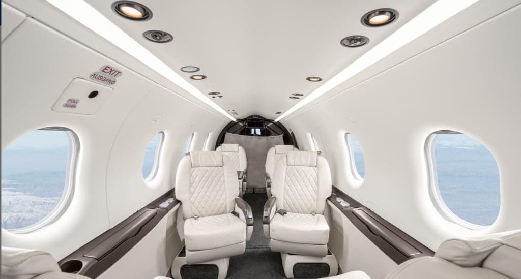 Interior view of the aircraft cabin with white leather seats.