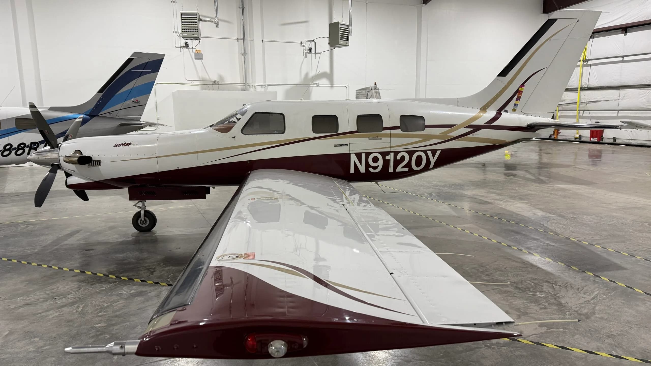 A white and maroon JetPROP aircraft with registration N9120Y parked in a hangar.