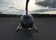 Front view of a black Robinson helicopter on the tarmac.