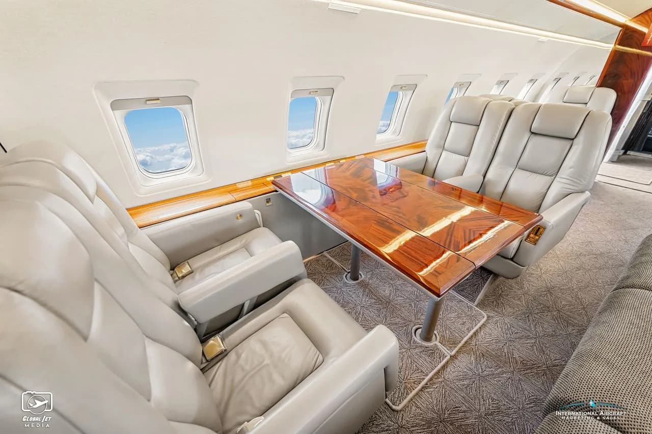Interior view of the aircraft cabin with leather seats and a wooden table.