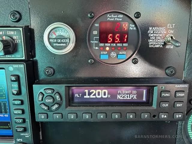 A close-up of the Mooney M20J instrument panel, showing a fuel flow gauge, prop de-icer gauge, and a Garmin transponder displaying "ALT 1200" and "N231PX".