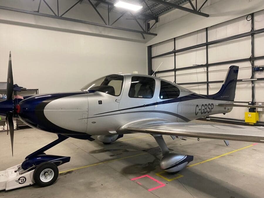 A Cirrus aircraft is being towed inside a hangar.