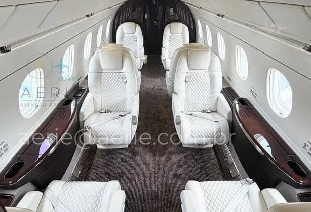 The luxurious main cabin of the aircraft with white quilted leather seats arranged in a club configuration.