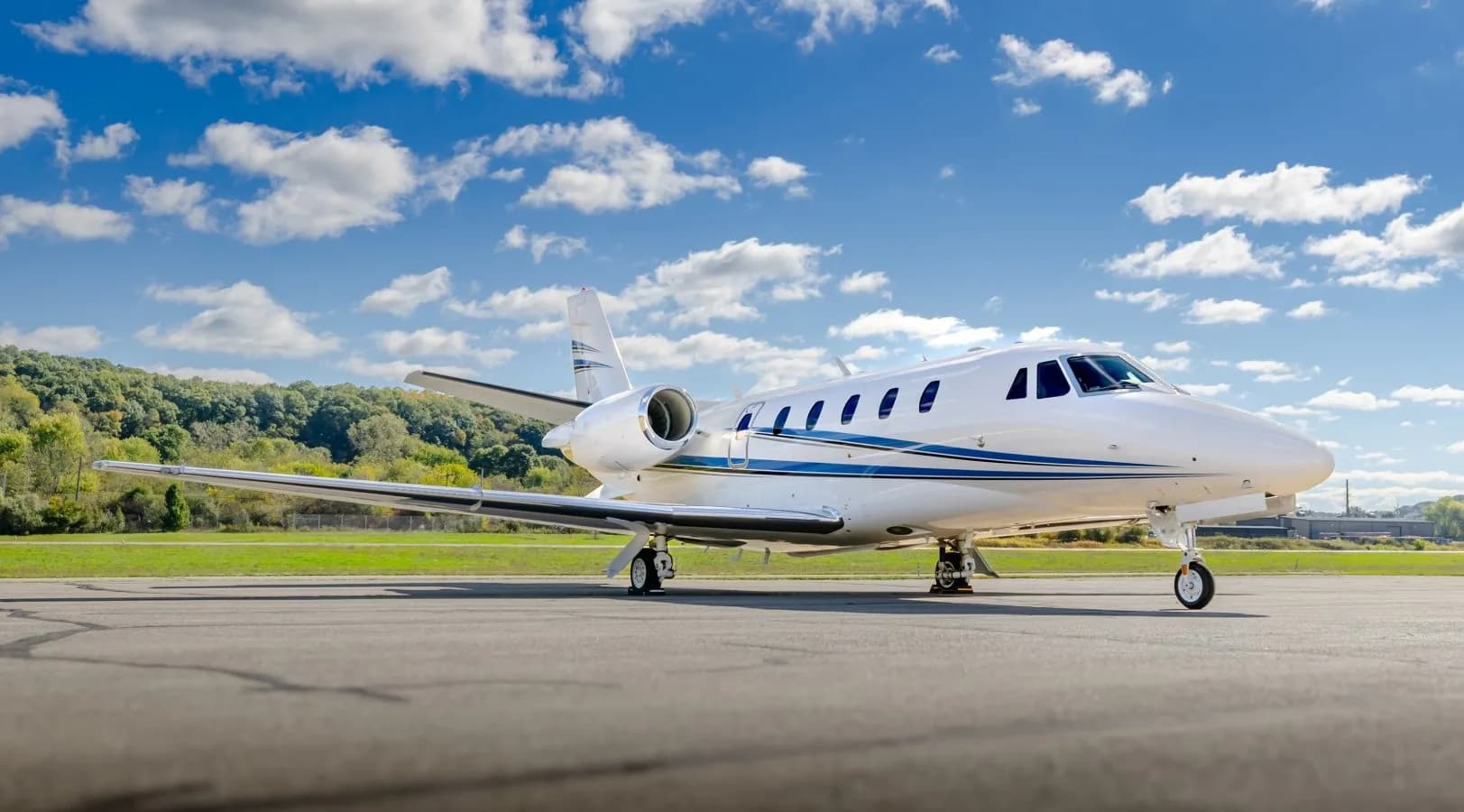 Side view of a white Citation jet with blue stripes on the tarmac.