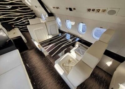 Interior view of the aircraft cabin with white leather seats and a table.