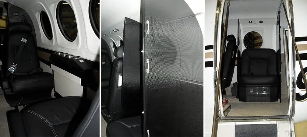 Interior view of the aircraft cabin with black leather seats and a partition.