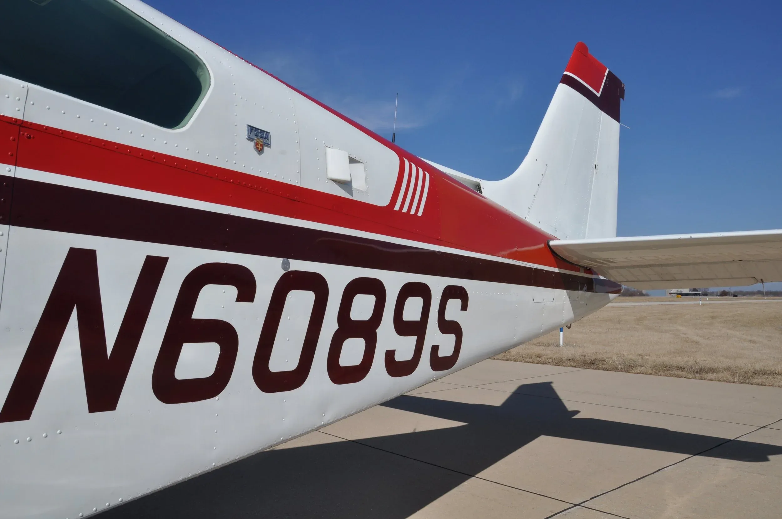 A close-up of the aircraft's tail section, clearly showing the registration N6089S and red stripe.