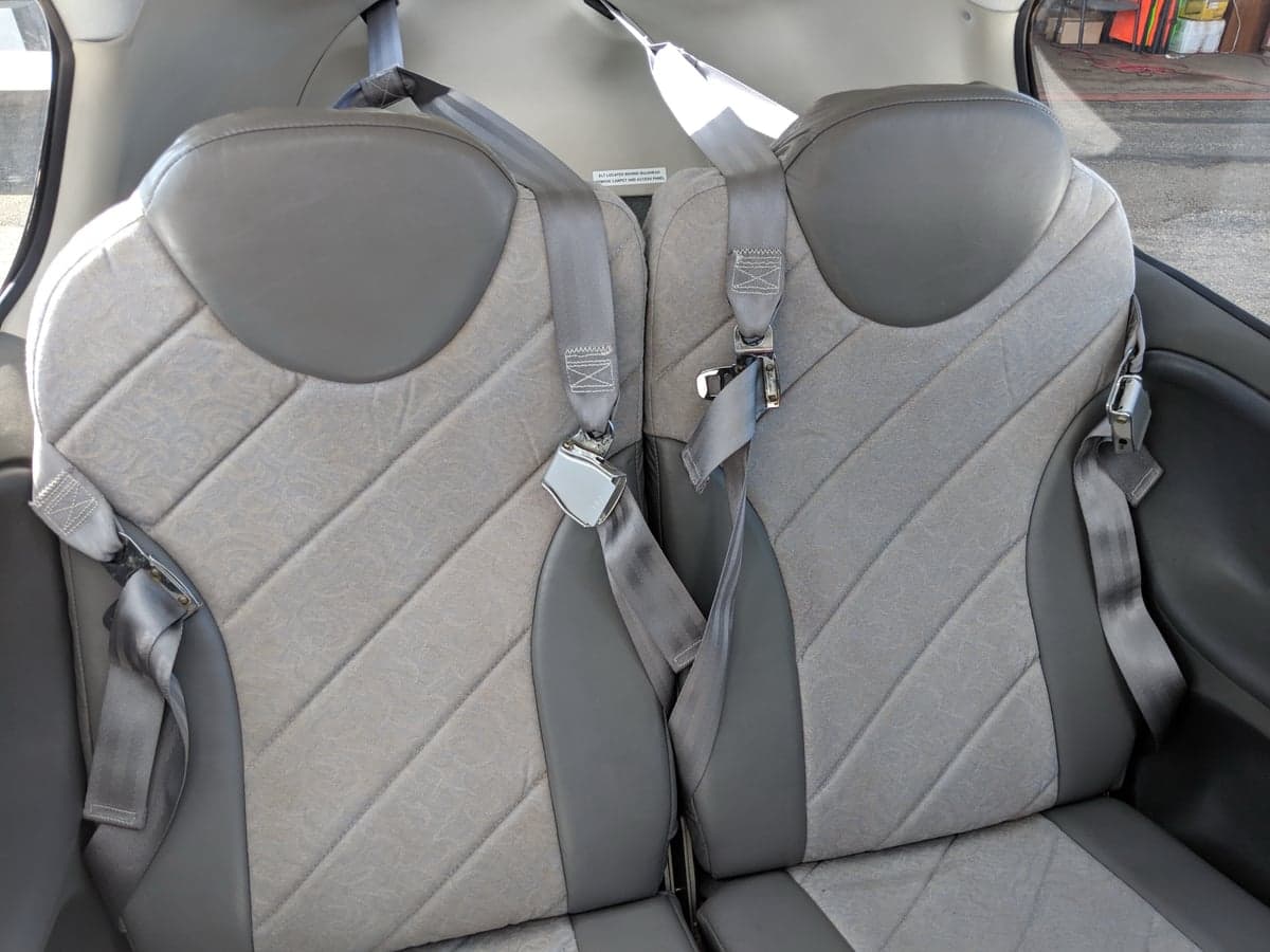 A close-up view of two gray passenger seats with seatbelts in the cabin of a Cirrus SR20 aircraft.