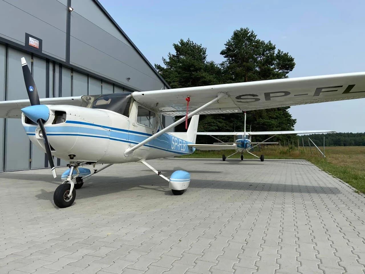 Cessna 150 with blue and white paint scheme parked on a paved surface.