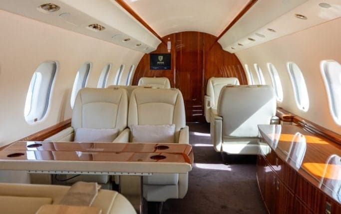 Aircraft cabin interior with cream-colored leather seats.