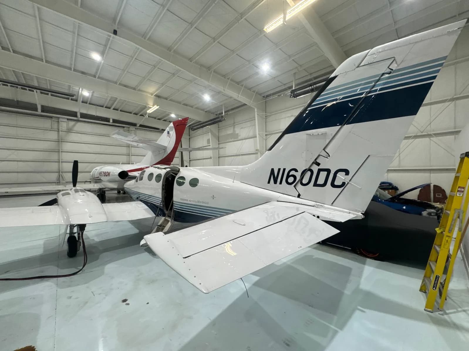 The tail of a Cessna 421 Golden Eagle with tail number N160DC parked in a hangar.