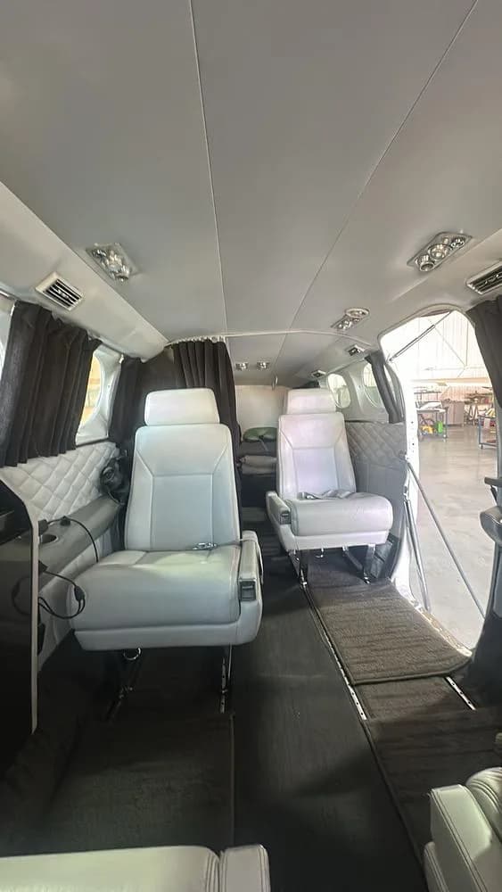 The spacious cabin interior of a Cessna 421 aircraft with light grey leather seats and quilted side panels, looking towards the rear.