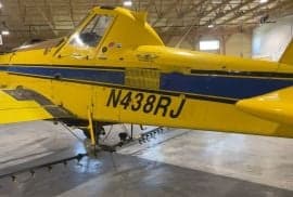 Close-up of the side of a yellow and blue agricultural aircraft with the tail number N438RJ.