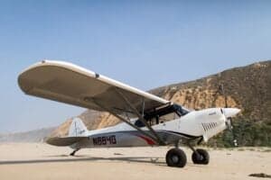 N864G aircraft on a beach with mountains in the background.