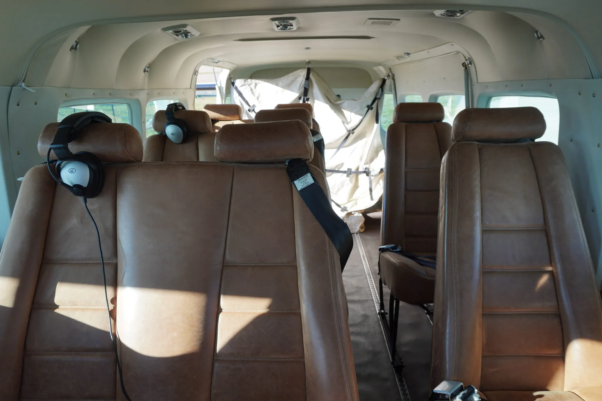 The aircraft's interior cabin features multiple rows of brown leather seats with headphones on the front seats.