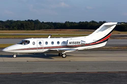 Side view of a white Eclipse 500 aircraft with registration N156RK on the tarmac.