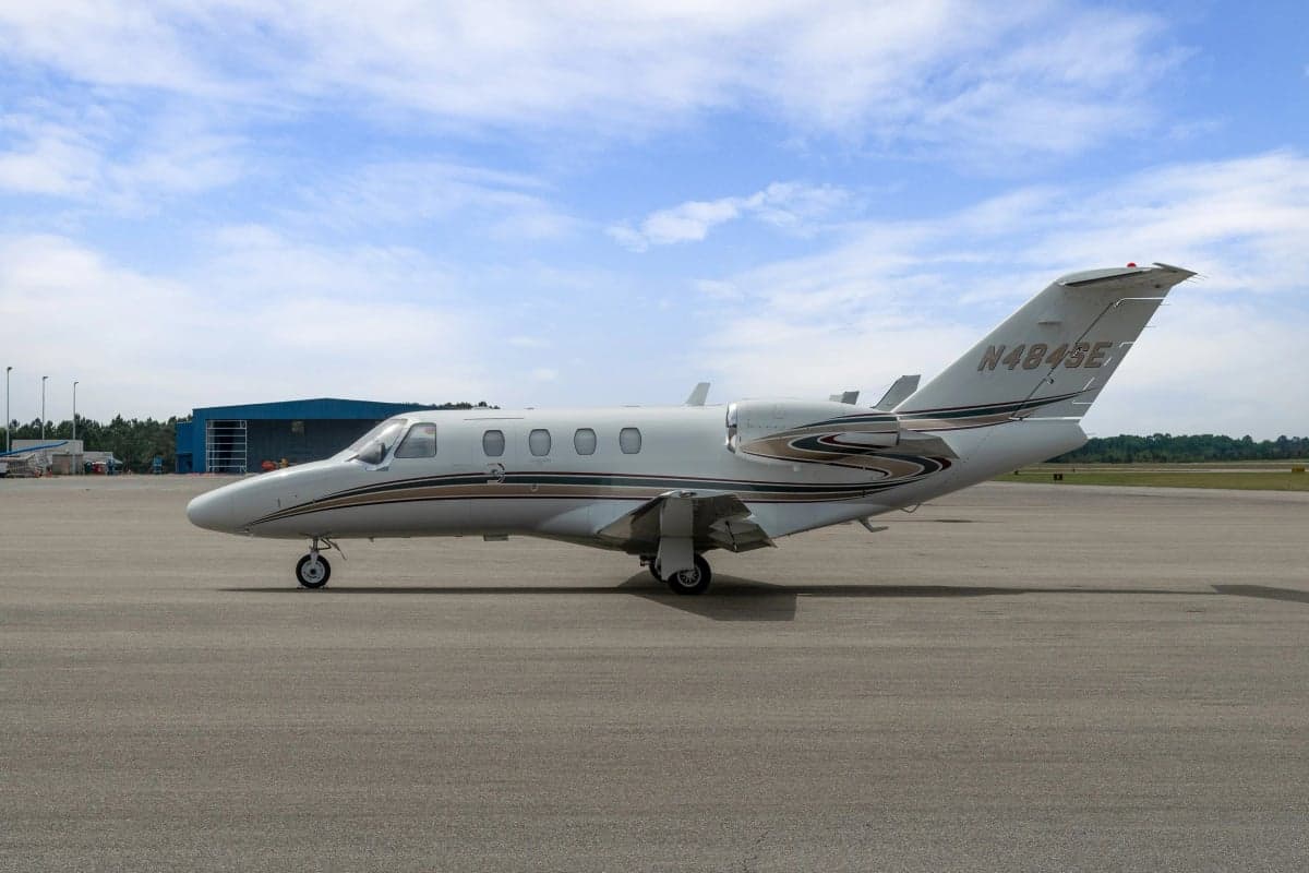 A Cessna Citation CJ1 parked on the tarmac in front of a hangar.