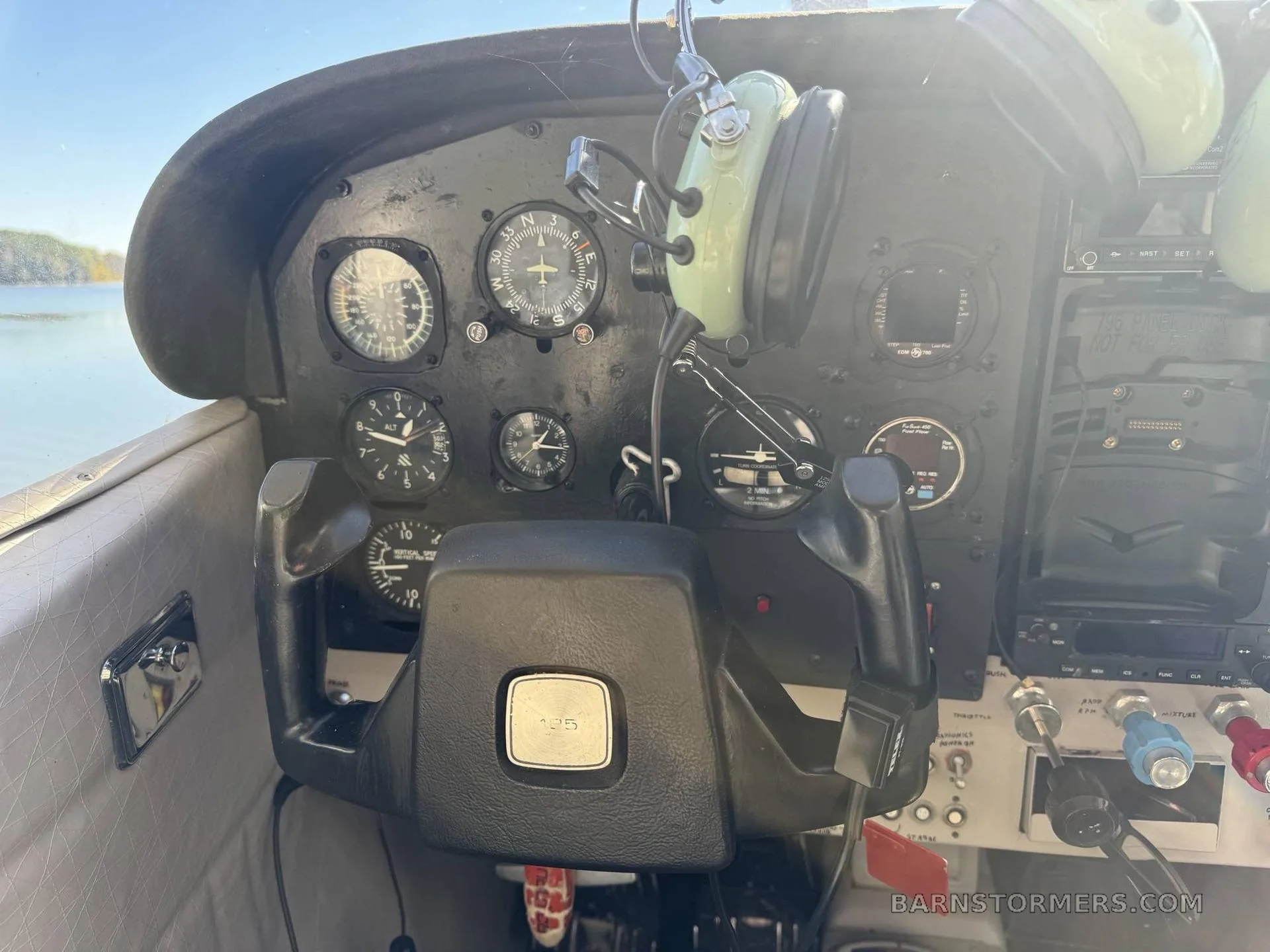 The instrument panel of the aircraft, featuring gauges, controls, and a headset hanging above.