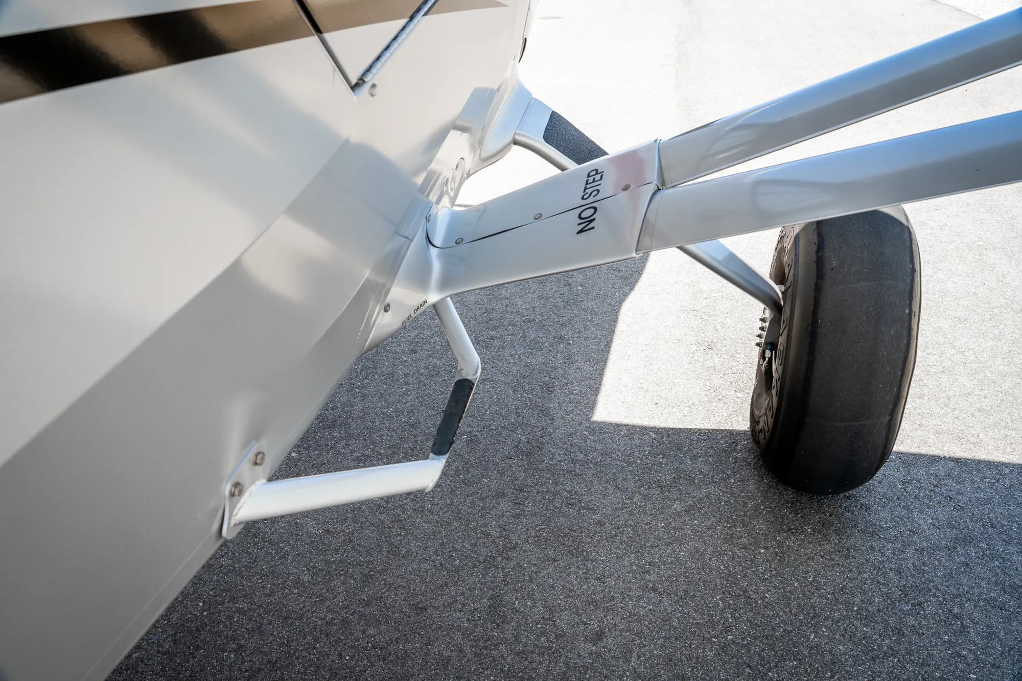 Close up of the step and landing gear of a white and gray CubCrafters XCub aircraft.