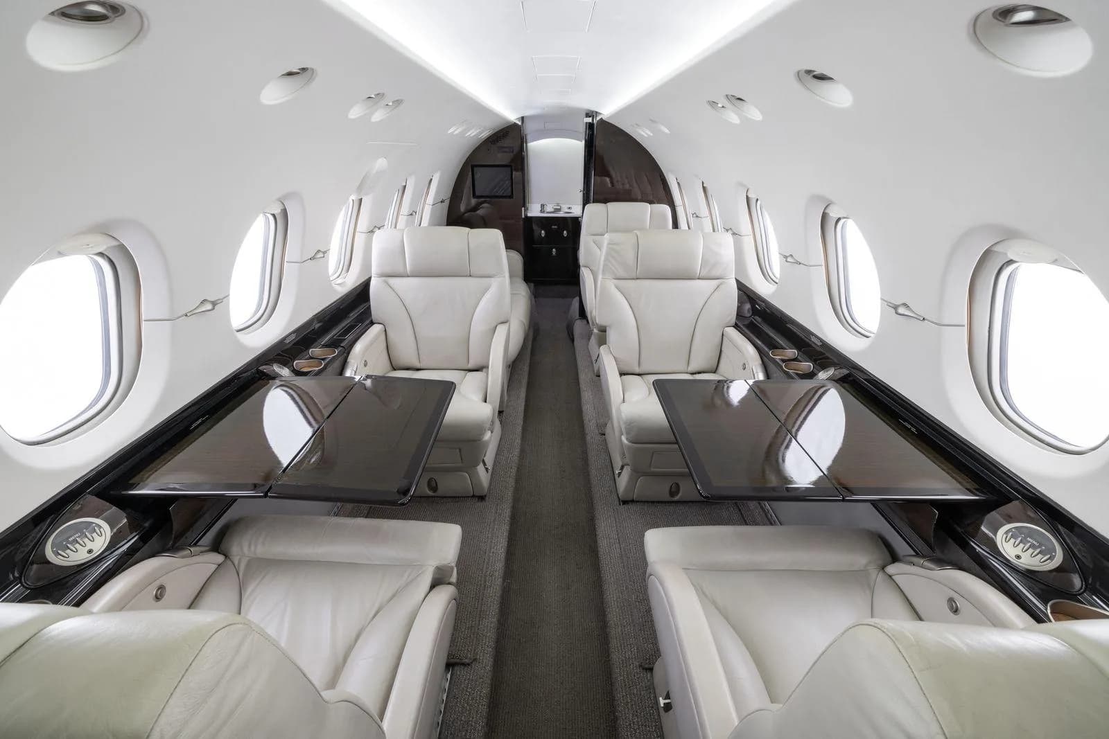 The aircraft's cabin interior with light-colored leather seats and dark fold-out tables.