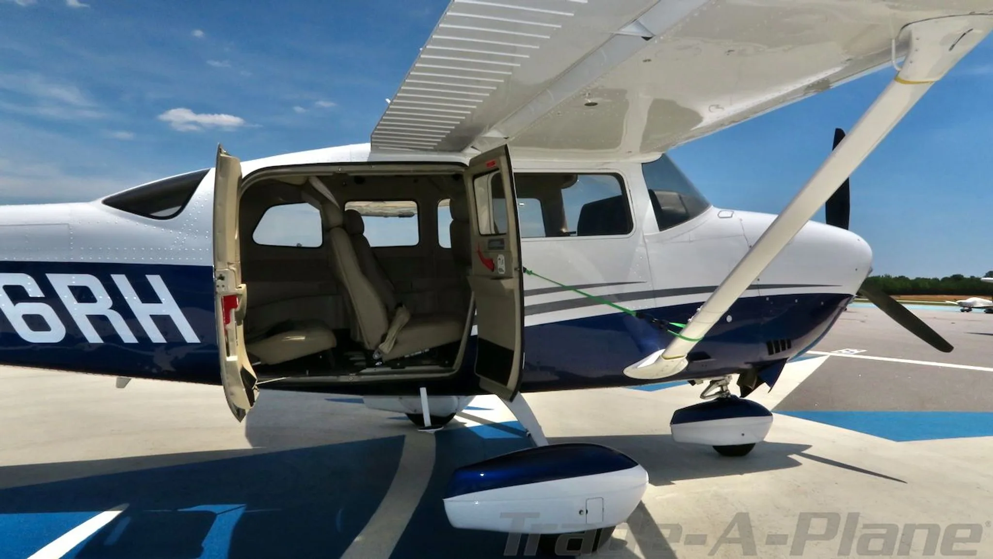 Front-right view of a white and blue Cessna Stationair HD (N36RH) with the passenger doors open, showing the interior.