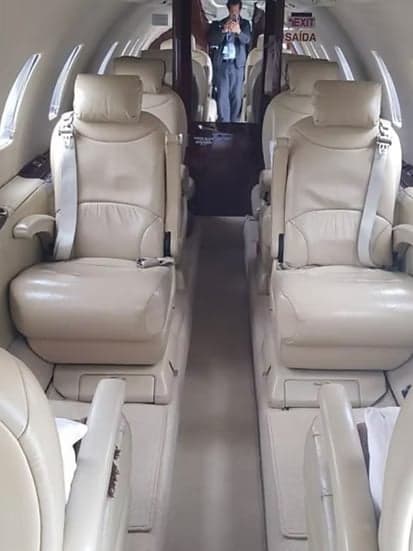 A view down the aisle of the aircraft cabin with tan leather seats.
