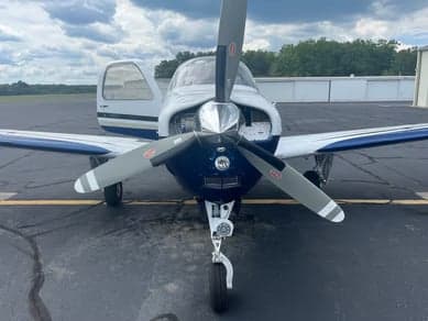 Beechcraft Bonanza parked on the tarmac under a cloudy sky.