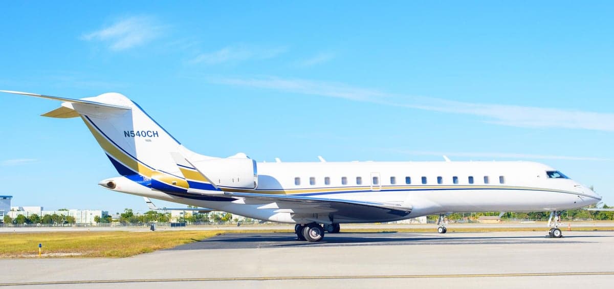 A white and gold Bombardier Global Express sits on the tarmac.