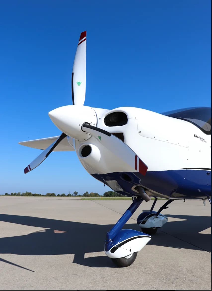 A close-up view of the propeller and nose of the white and blue Tecnam P2010 aircraft.