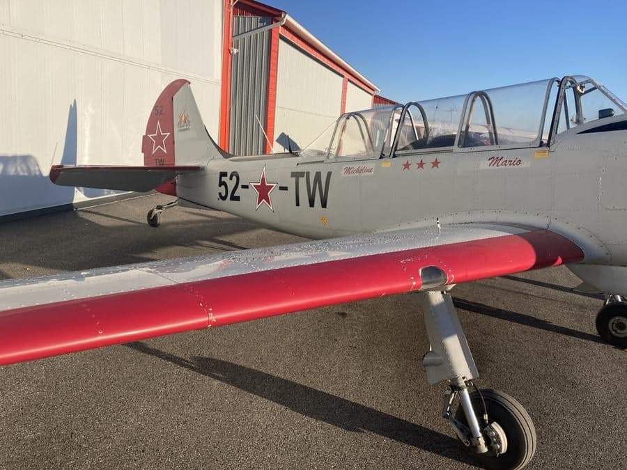 Close-up of the tail and wing of a Yak-52TW aircraft with red accents.
