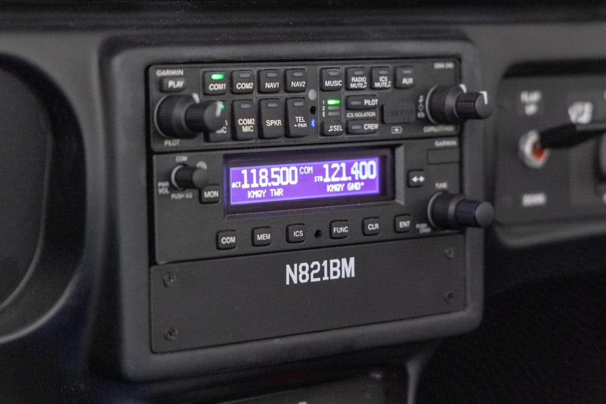 A close-up of the aircraft's radio stack, displaying communication frequencies and the registration N821BM.
