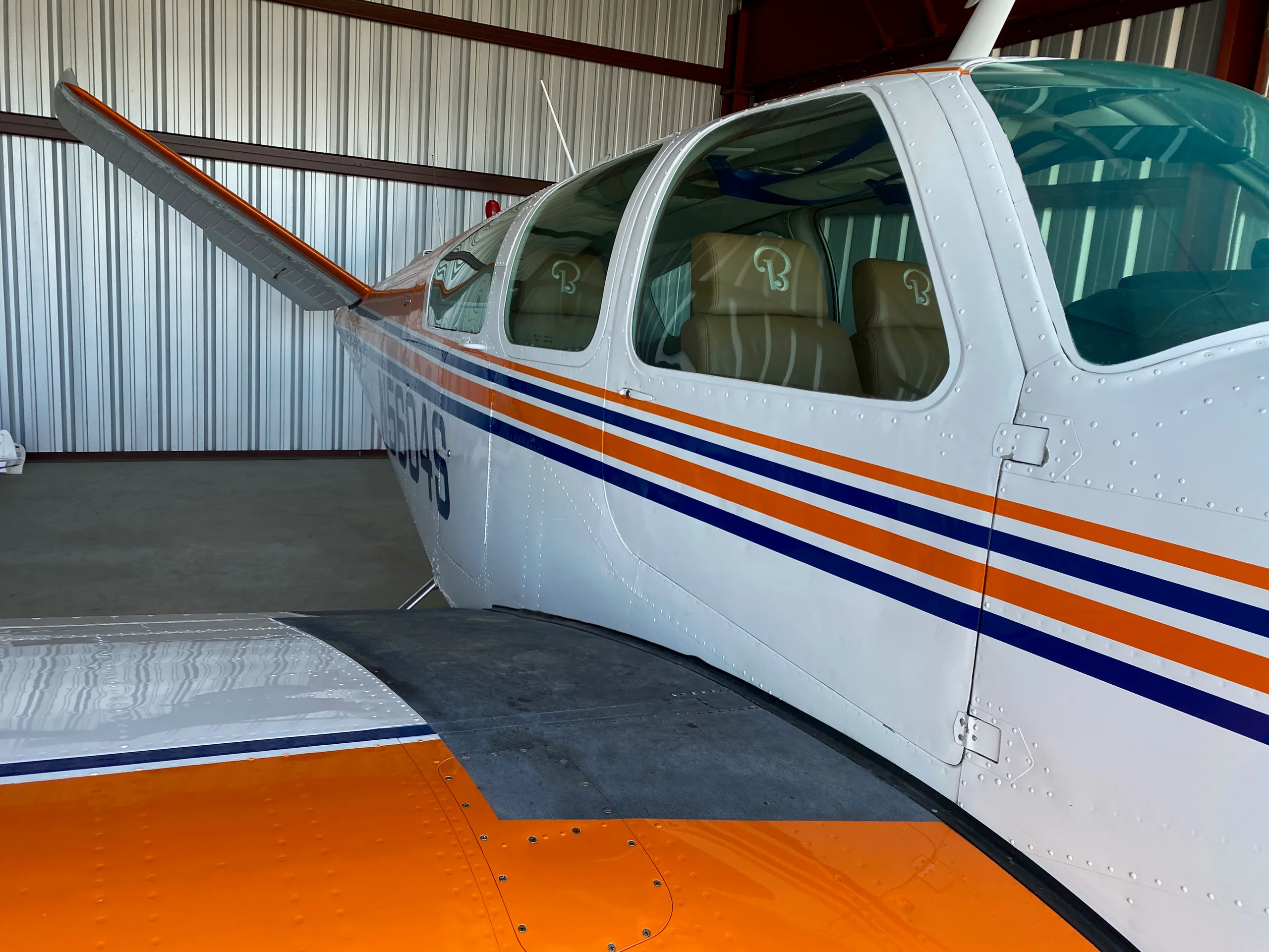 Close-up of the side of a Beechcraft V35 Bonanza aircraft with registration N5604S, showing the cabin windows and paint scheme.