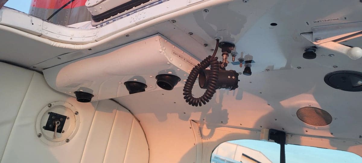 A view of the aircraft's cockpit ceiling with various vents and controls.