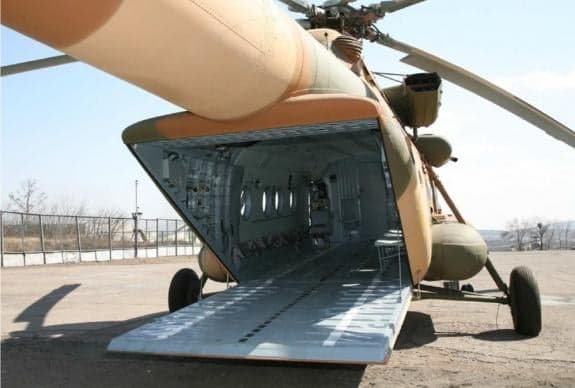 The open cargo bay of a camouflaged helicopter is visible.