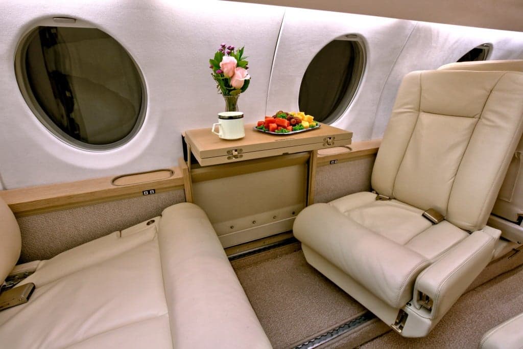 Close-up of the Hawker 4000 cabin seating area with a small table and refreshments.