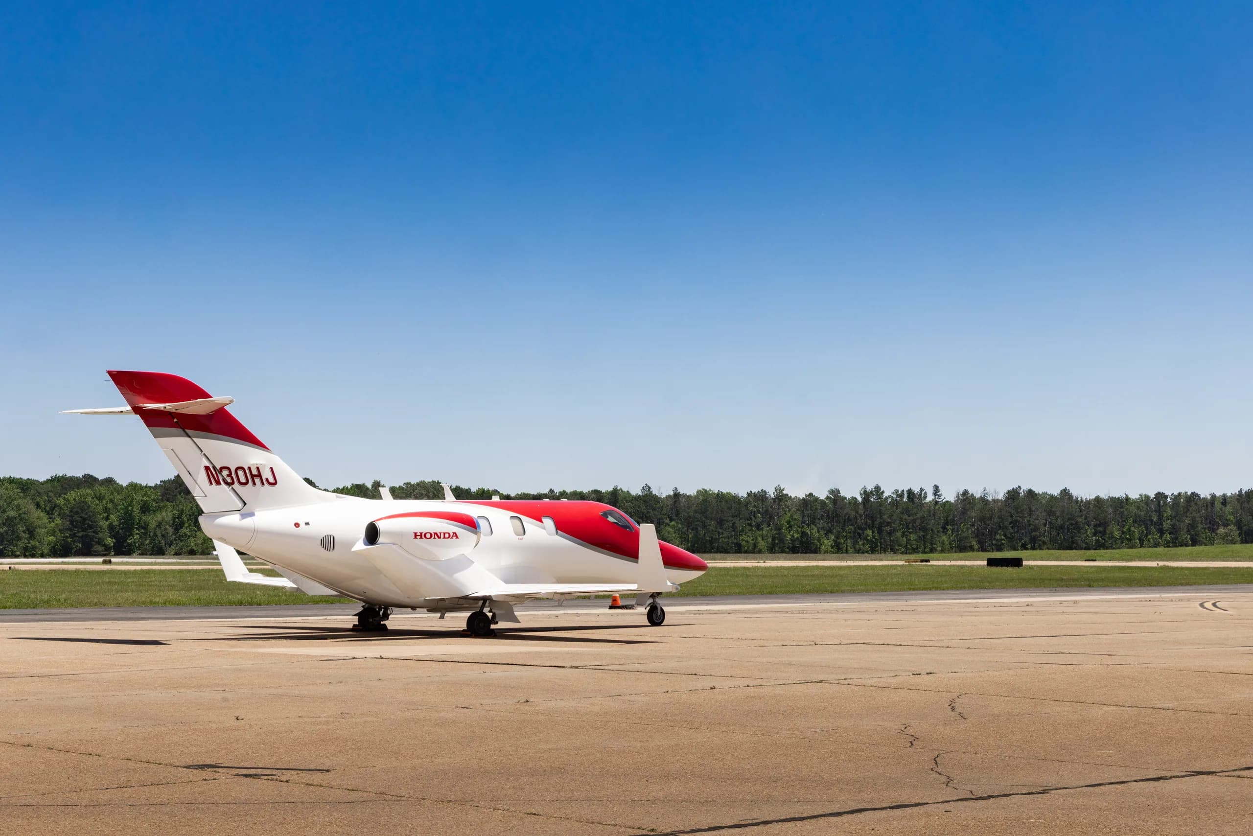 A white and red HondaJet HA-420 (N30HJ) parked on a tarmac, viewed from the rear-right.