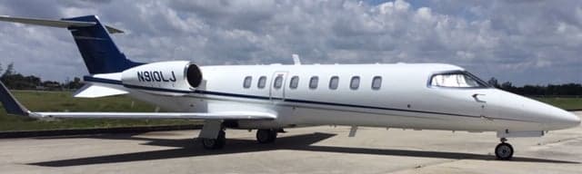 Side view of a white and blue Learjet on the tarmac.