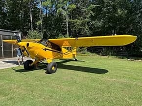 A yellow Carbon Cub EX aircraft parked on grass.