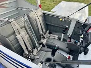 Interior view of the aircraft cabin with gray seats and seatbelts.