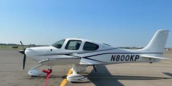 A white Cessna Skyhawk aircraft with black and red stripes, registration N5169E, parked in front of a hangar.
