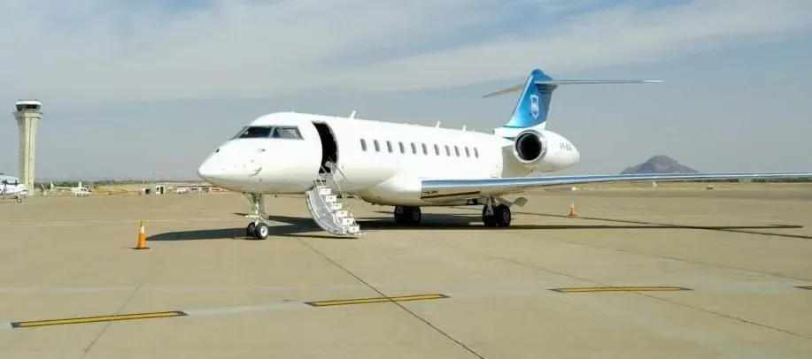 A white Bombardier Global Express business jet parked on the tarmac with the airstair deployed.