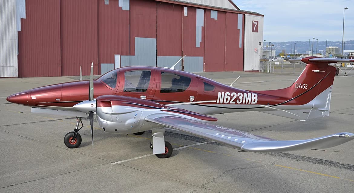 A maroon and silver Diamond DA62 aircraft is parked on the tarmac.