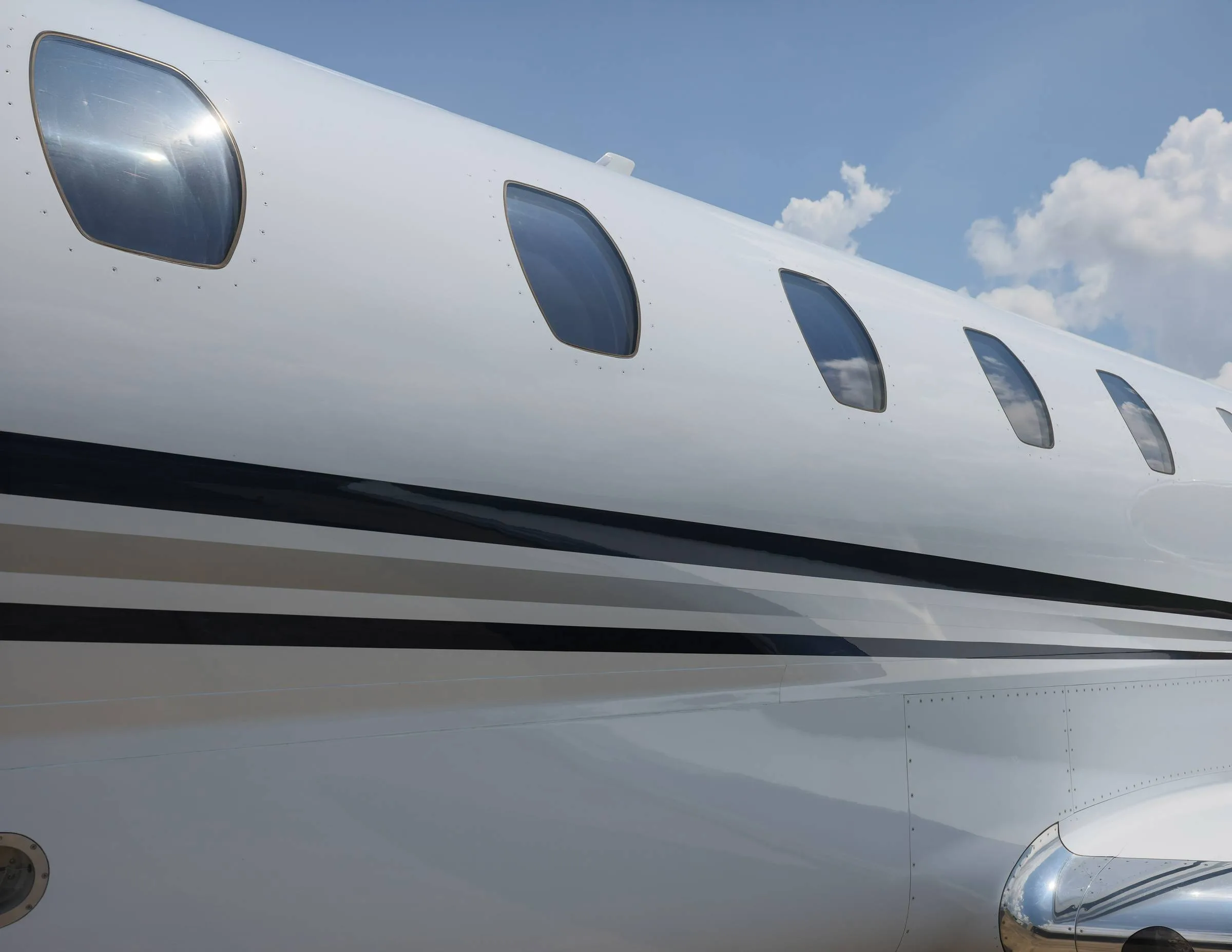 A close-up view of the white fuselage and windows of a business jet with black accent stripes.