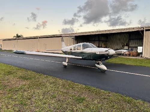 Piper PA-28-181 Archer II aircraft N1435T parked in front of a hangar.