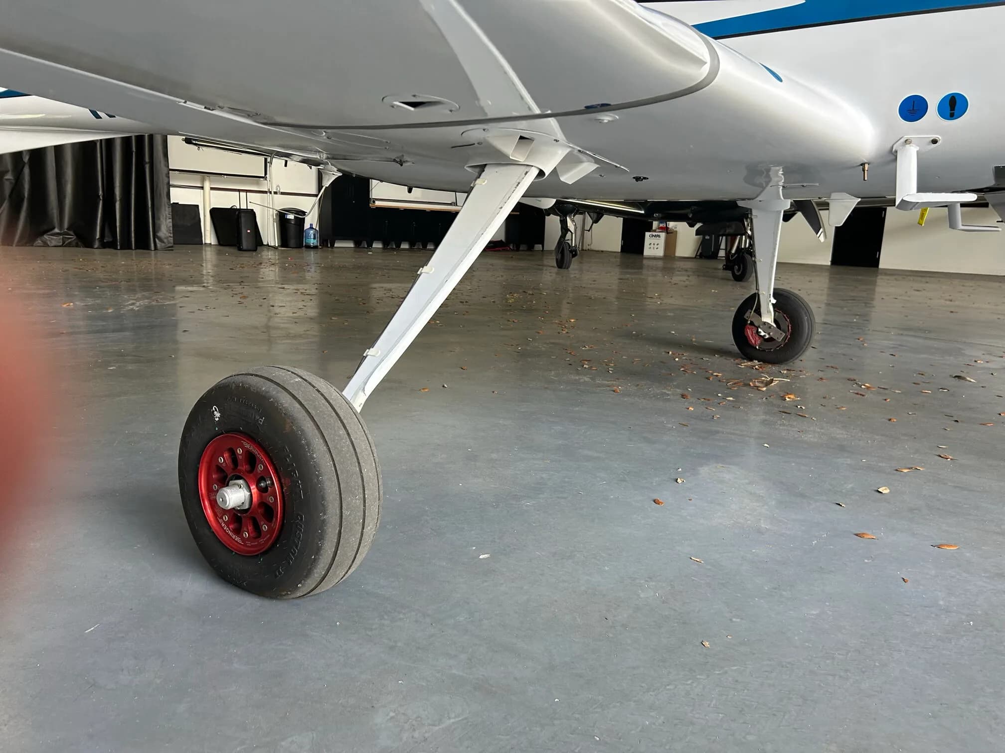 Close-up view of the main landing gear and wheel with red hub on a white Diamond DA40 aircraft.