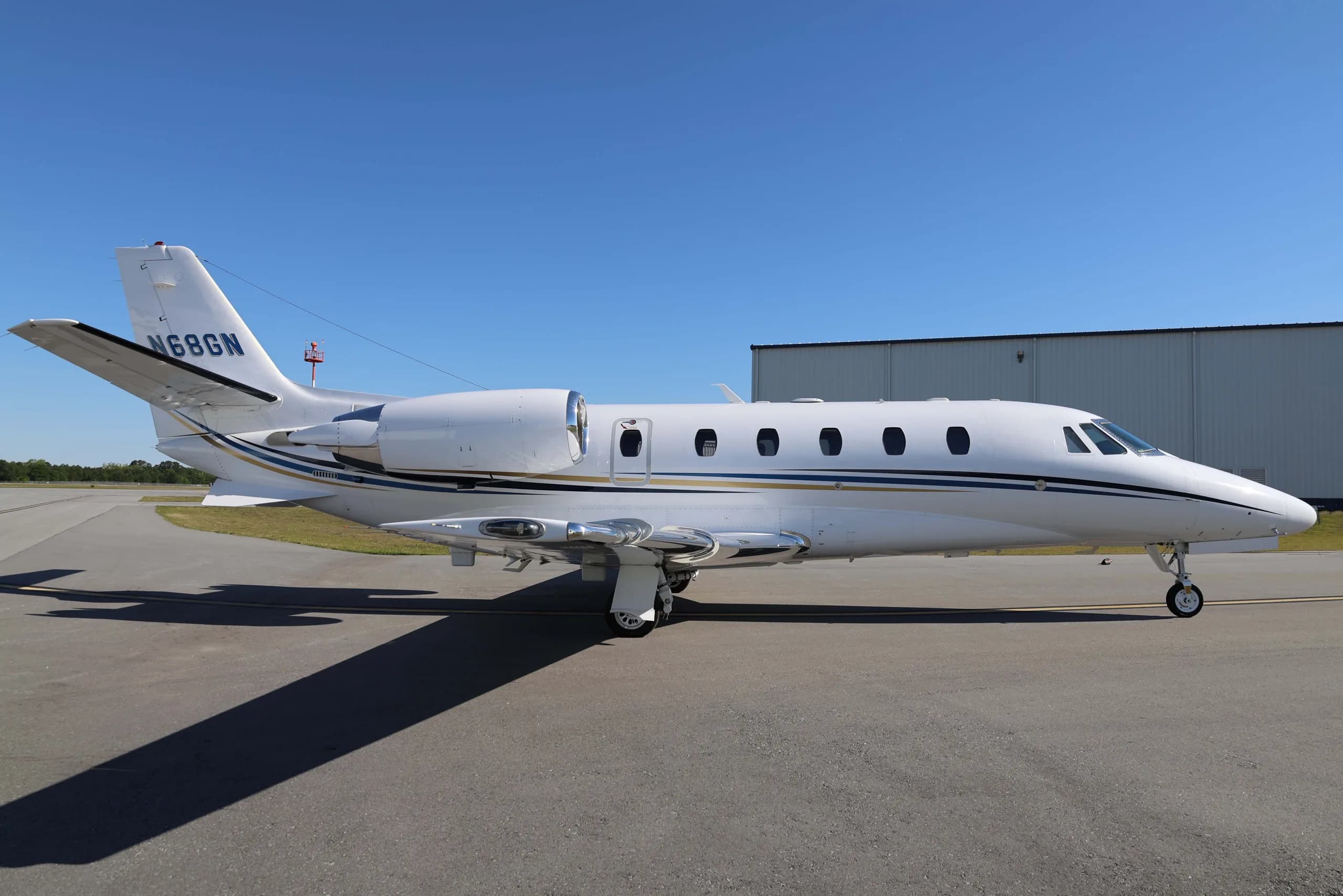A side view of the white Cessna Citation business jet N68GN on an airport tarmac.
