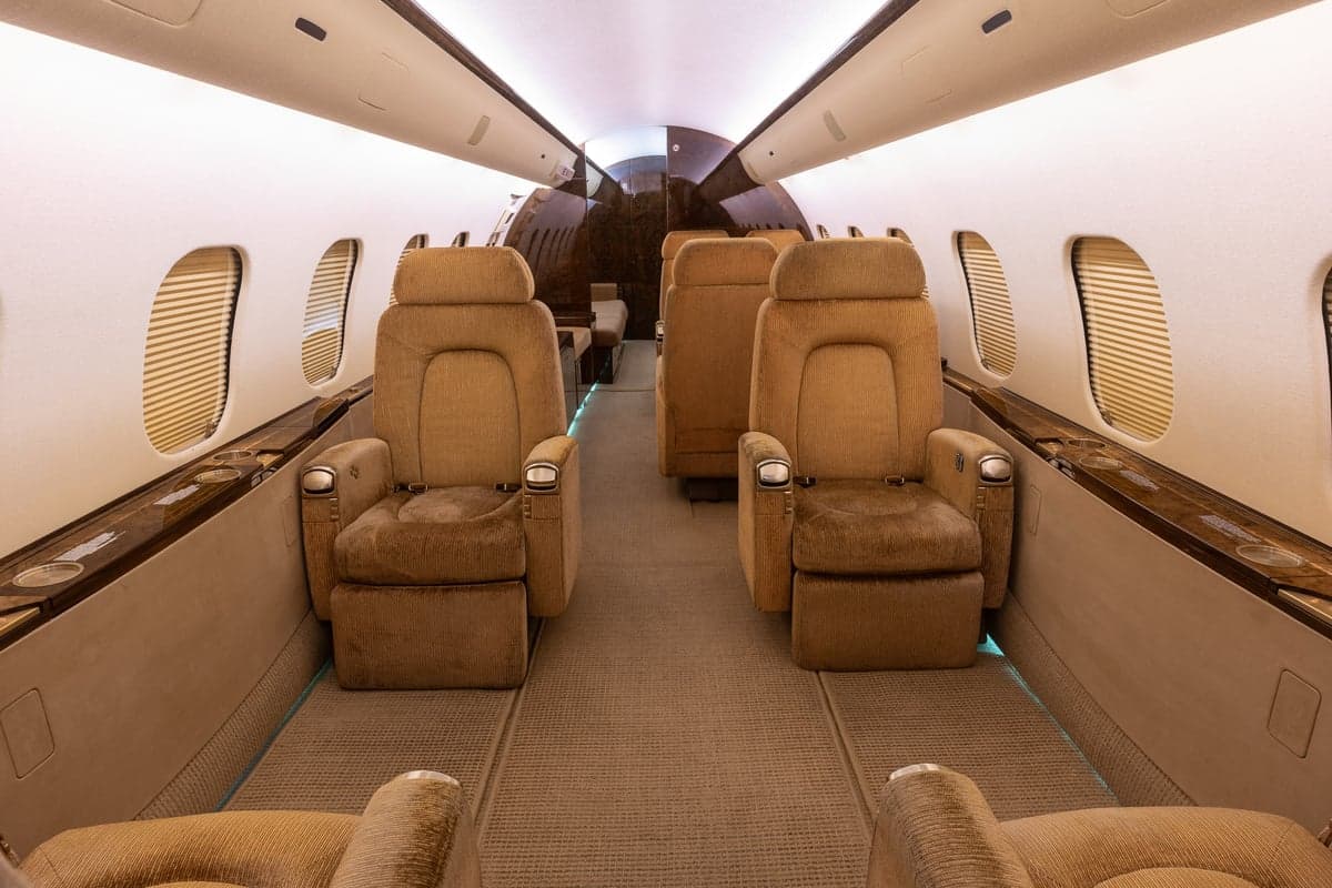 The interior of a Bombardier Global Express aircraft with tan leather seats and carpet.