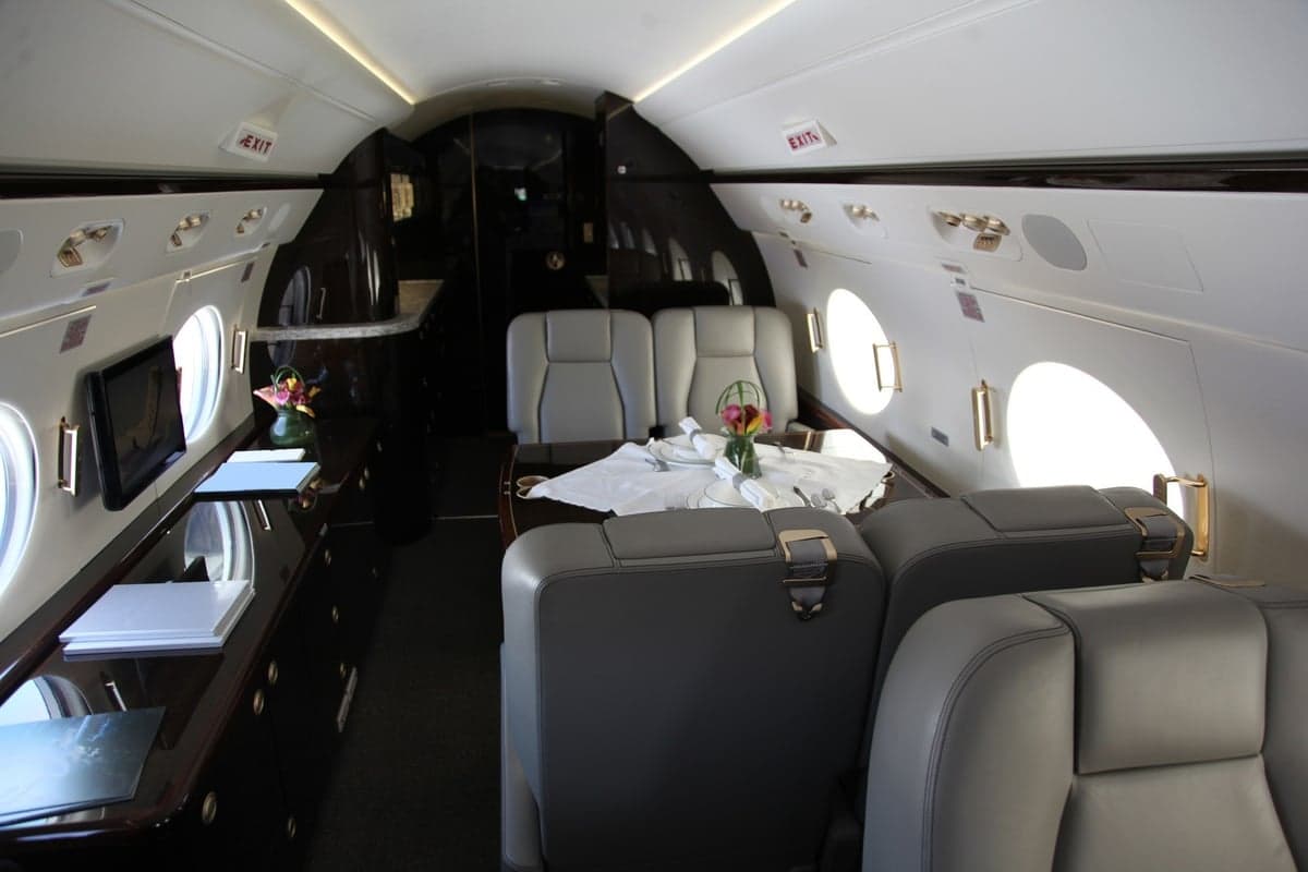 Interior view of an aircraft cabin with leather seats and a table set for dining.