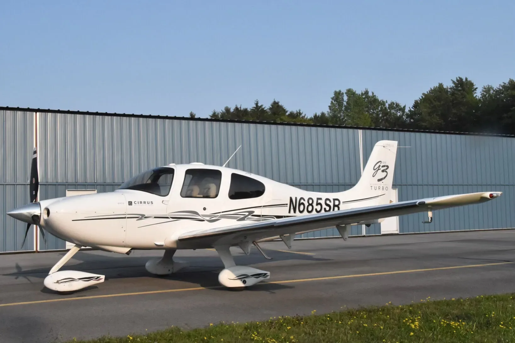 A white Cirrus SR22 G3 Turbo aircraft (N685SR) with black and grey accents parked on an airfield.