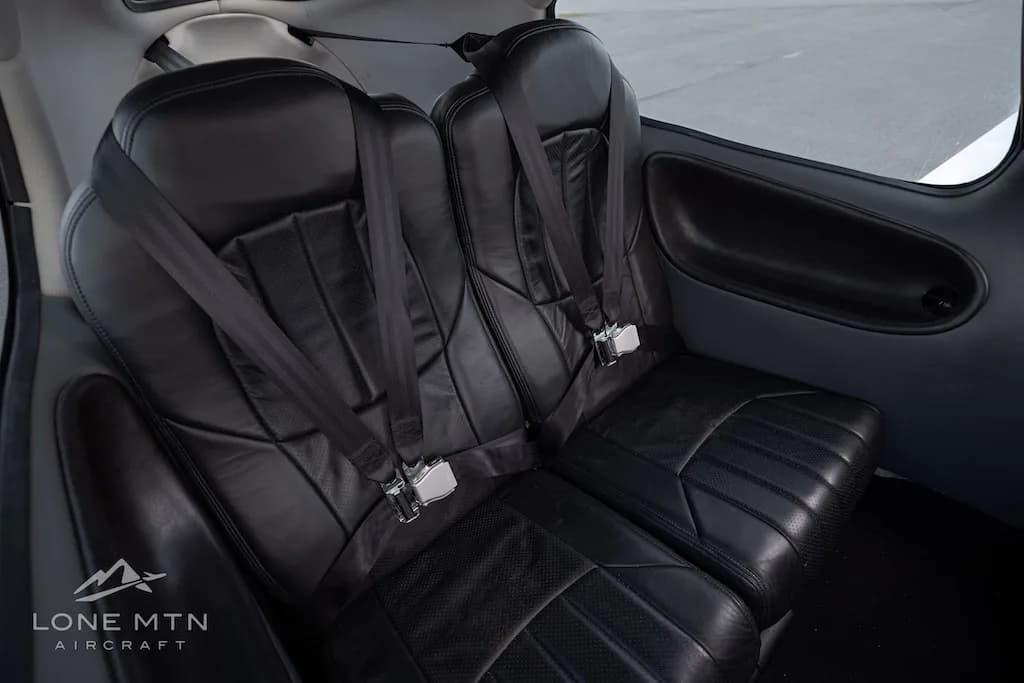 The black leather rear passenger seats with seatbelts inside the aircraft cabin.